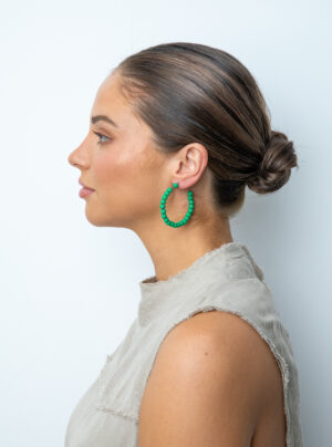 Girl wearing hoop earrings with green wooden beads