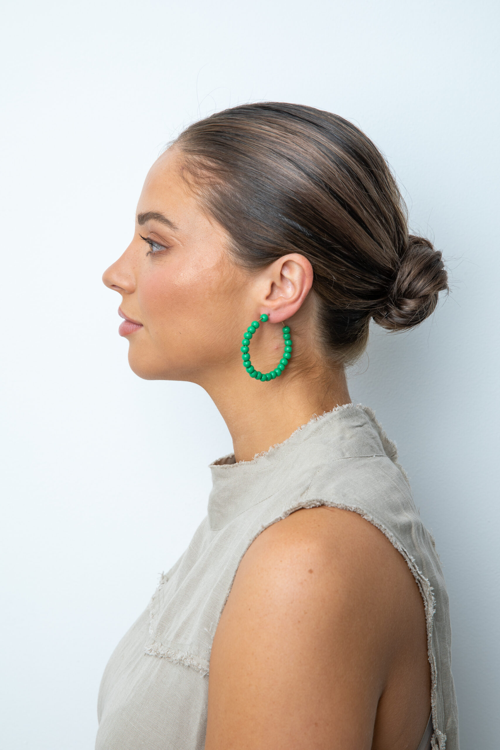 Girl wearing hoop earrings with green wooden beads