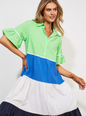 Girl wearing a bright coloured dress in green, blue and white with contrast ric-rac detail